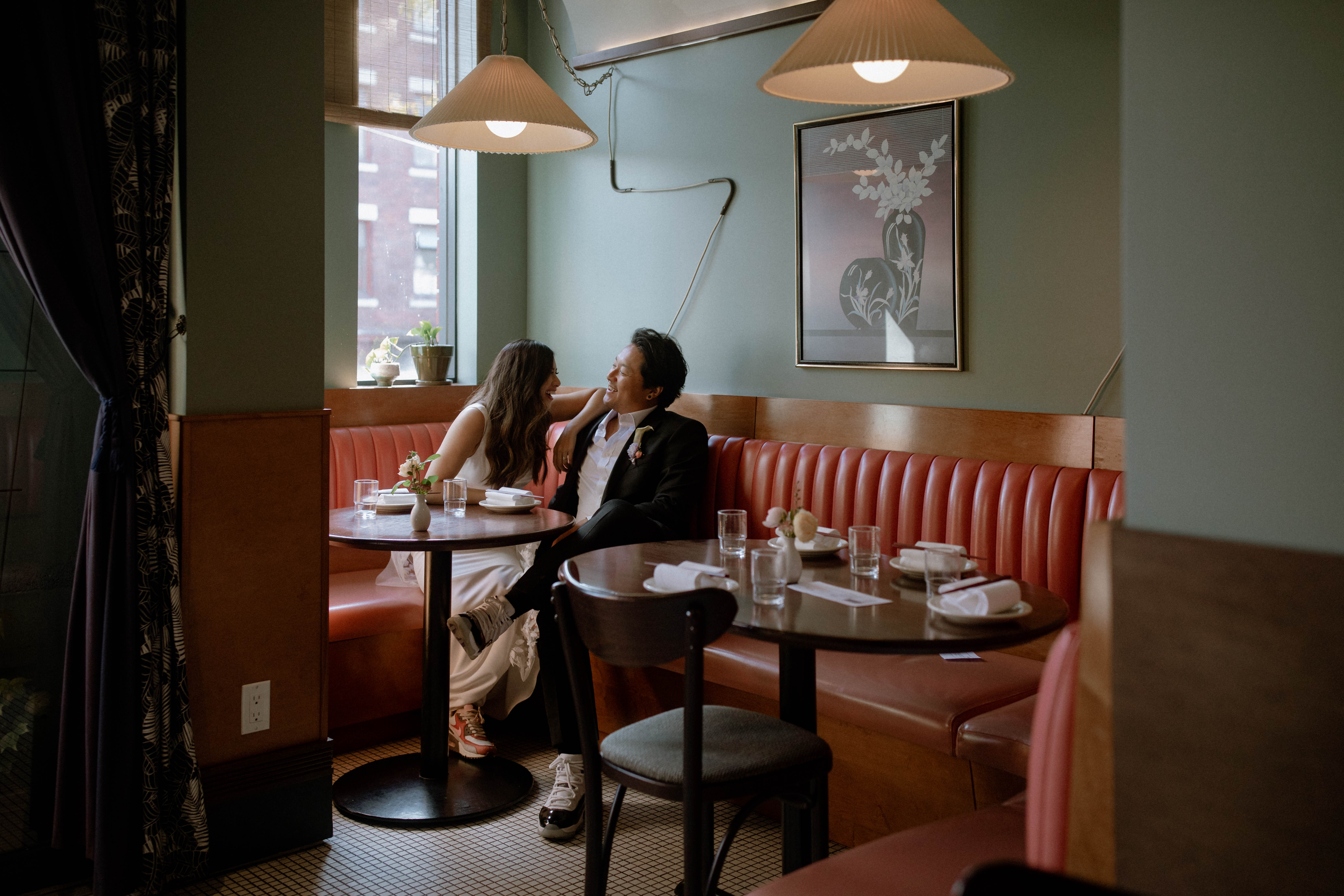 Wedding couple laughing together while seated inside Kissa Tanto in Vancouver