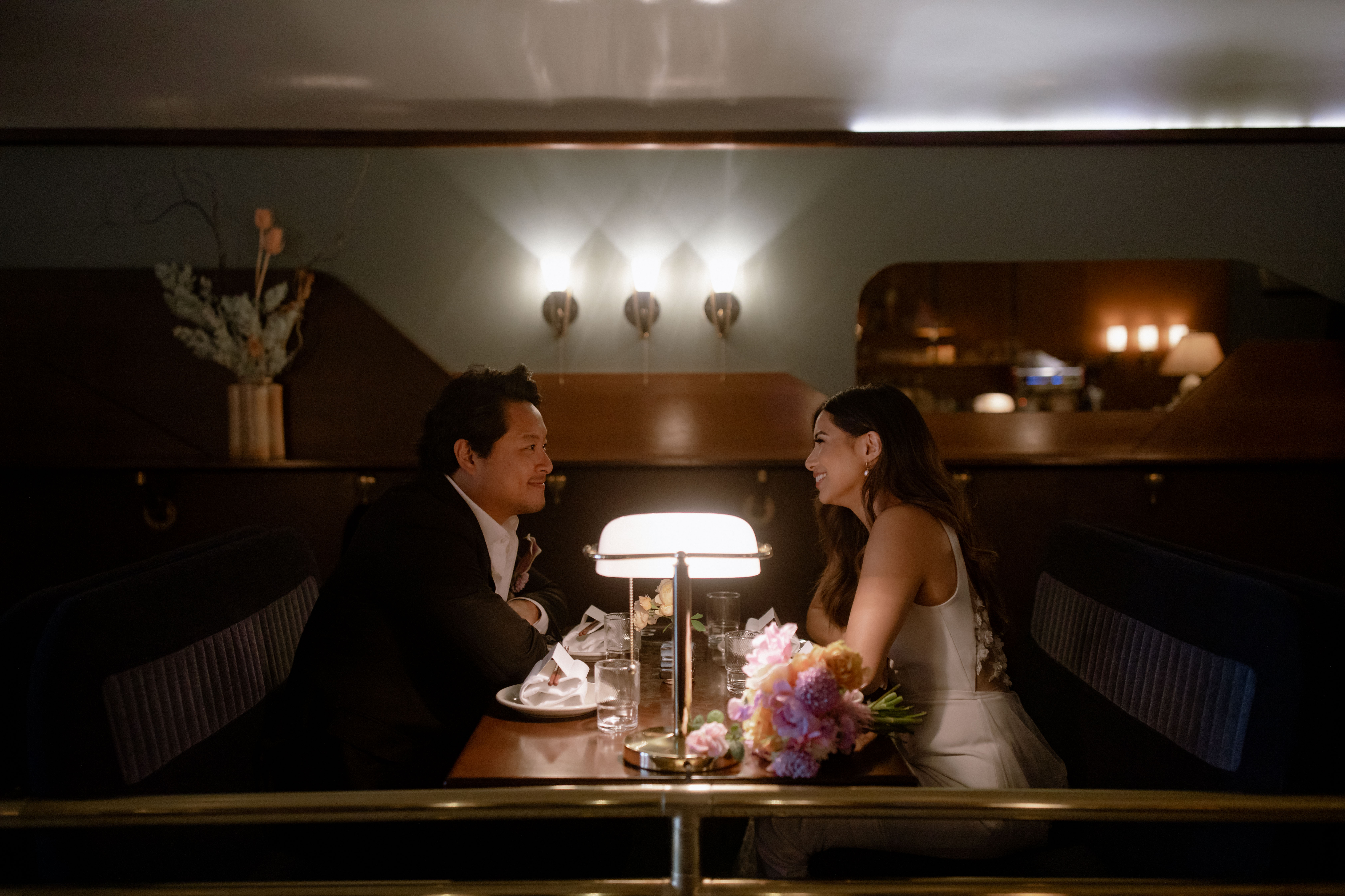 Wedding couple smiling at each other while sitting across at Kissa Tanto in Vancouver