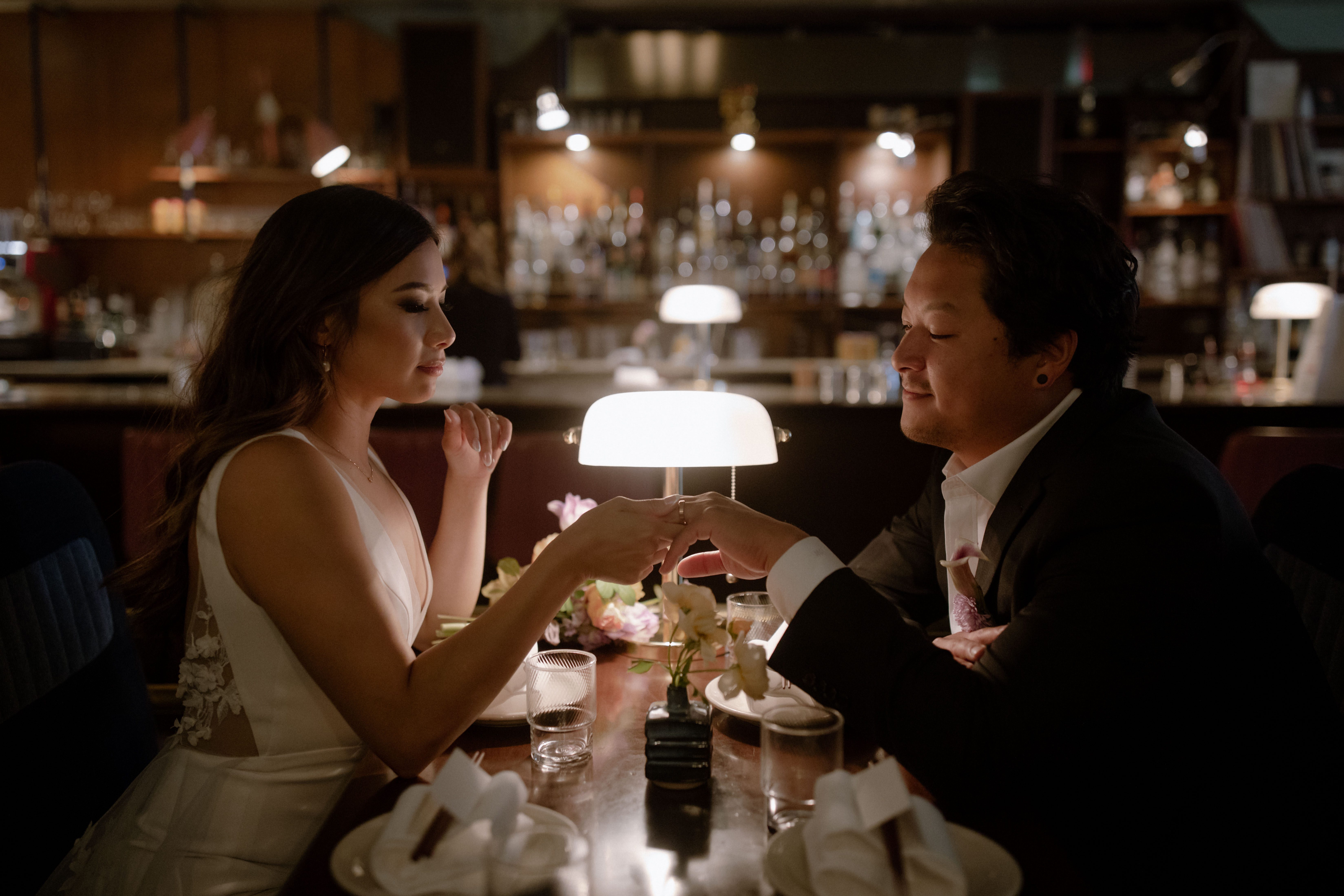 Wedding couple holding hands, sitting across from each other in Kissa Tanto, Vancouver