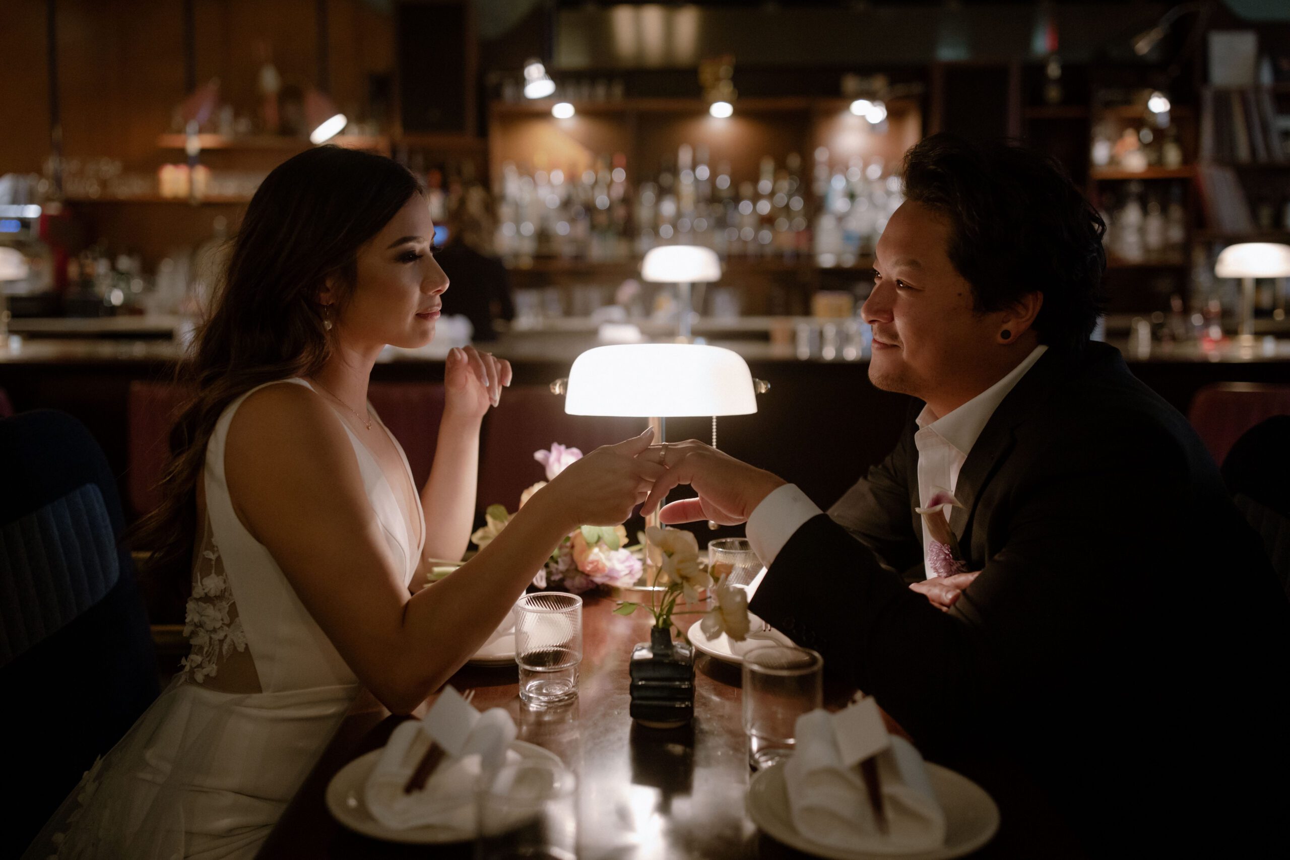 Wedding couple smiling at each other at a booth in Kissa Tanto.