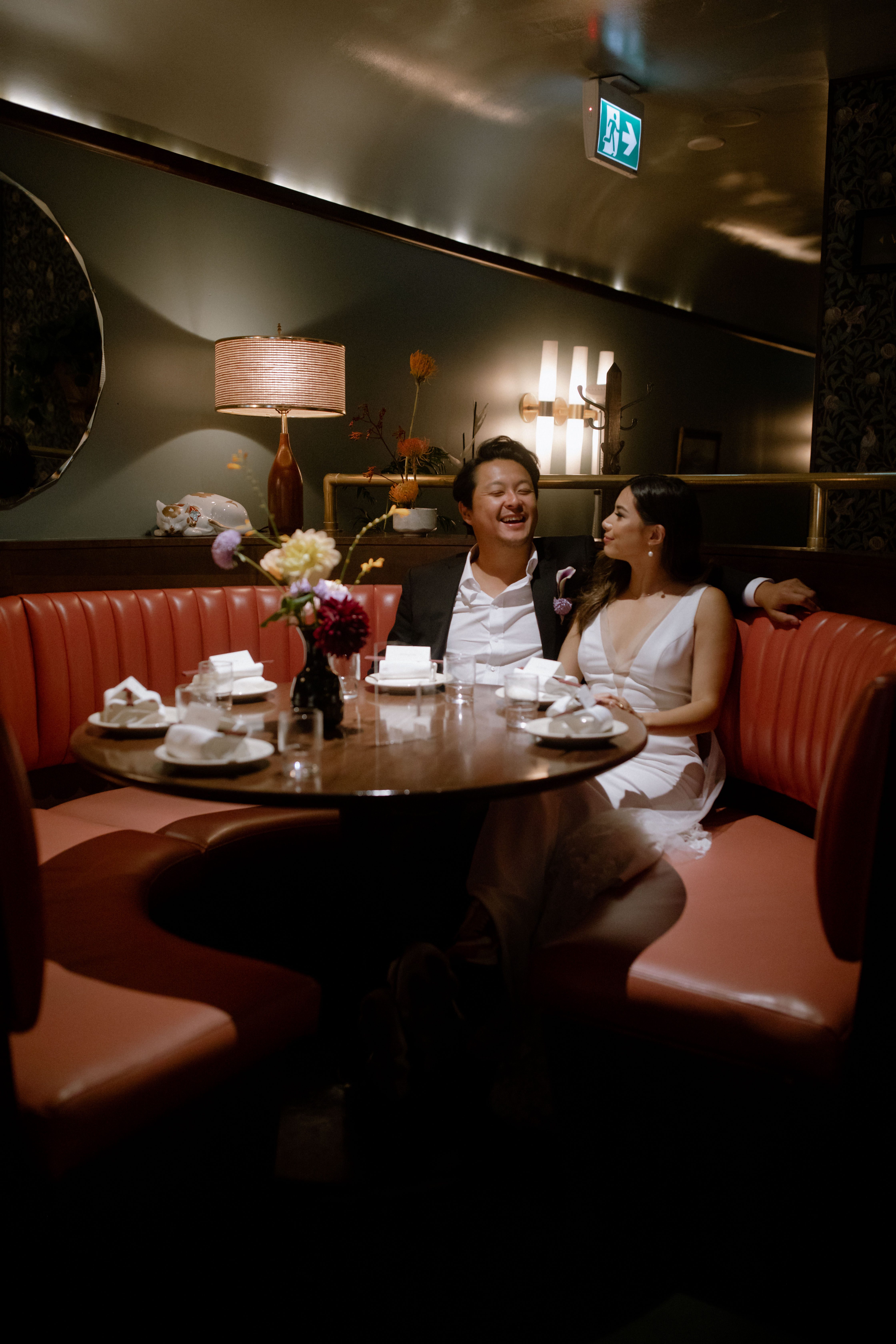 Married couple laughing together while sitting in a dining booth at Kissa Tanto, Vancouver