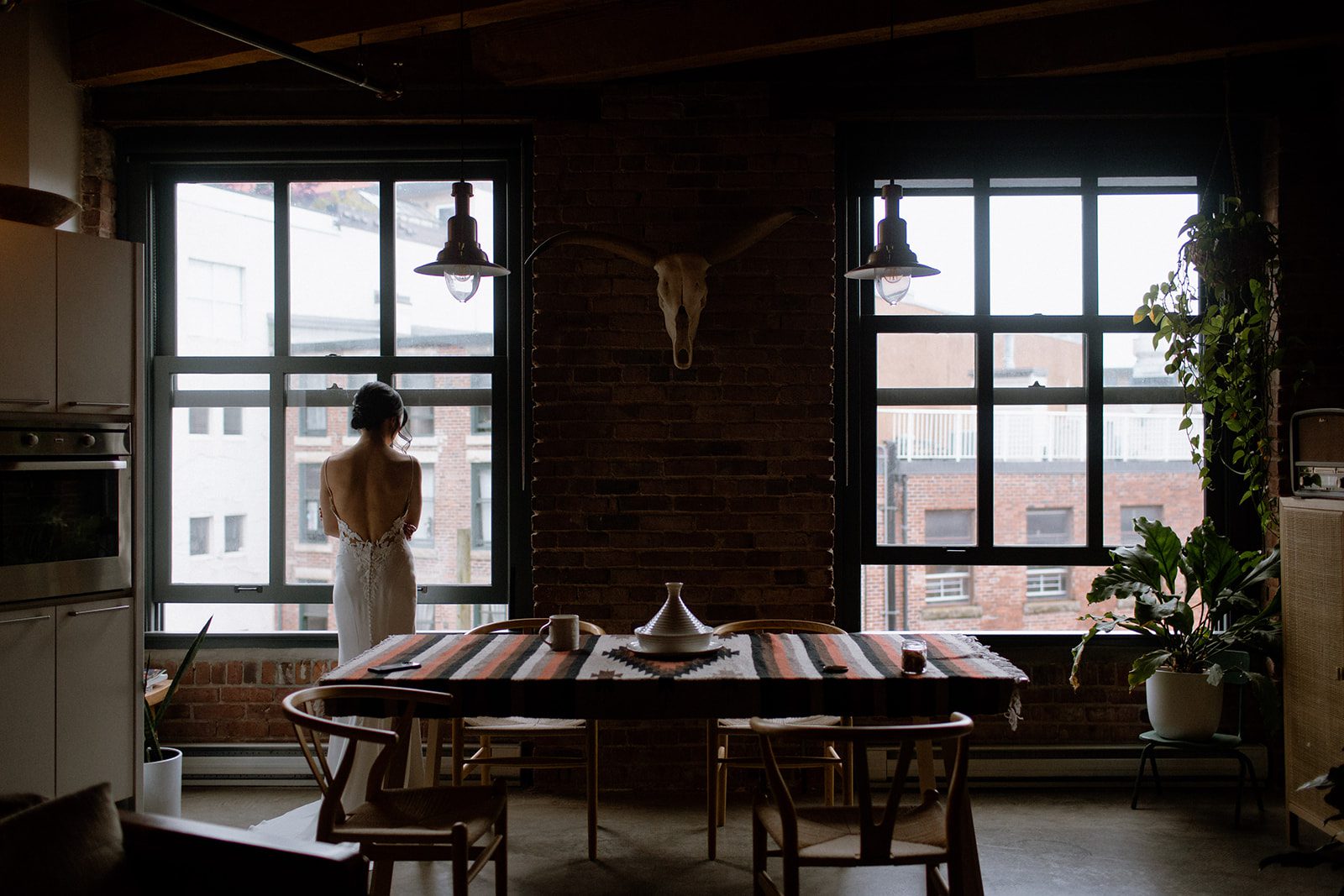Bride standing by the window in a Gastown loft, having a moment to herself before her wedding.